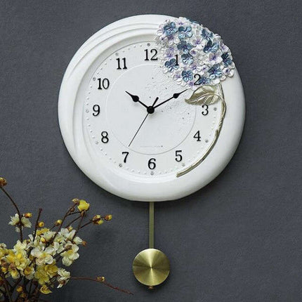 Hvit veggklokke med pendel og blomster